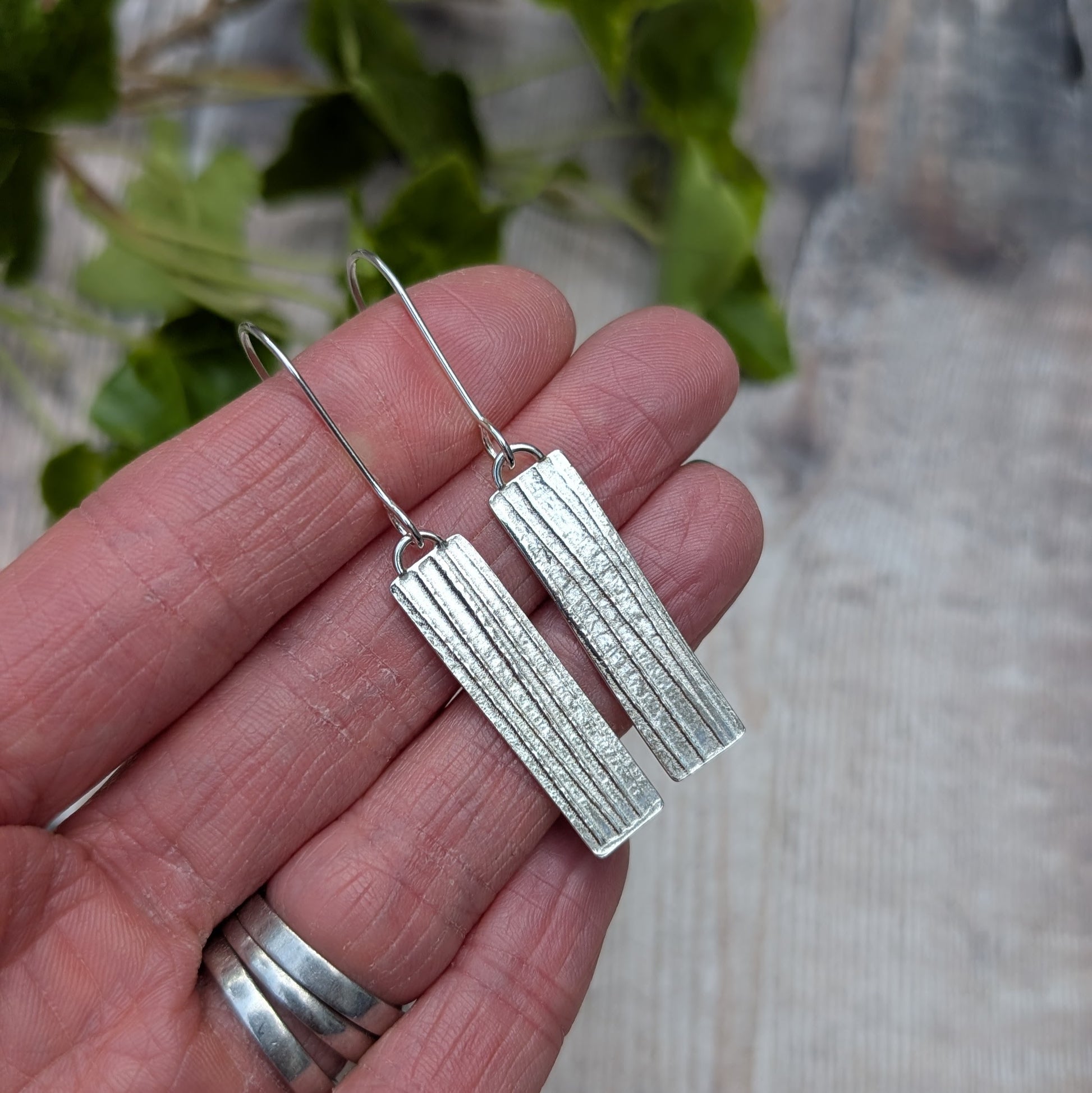 Silver Rectangle Earrings with Ribbon Pattern held in hand showing size and texture detail