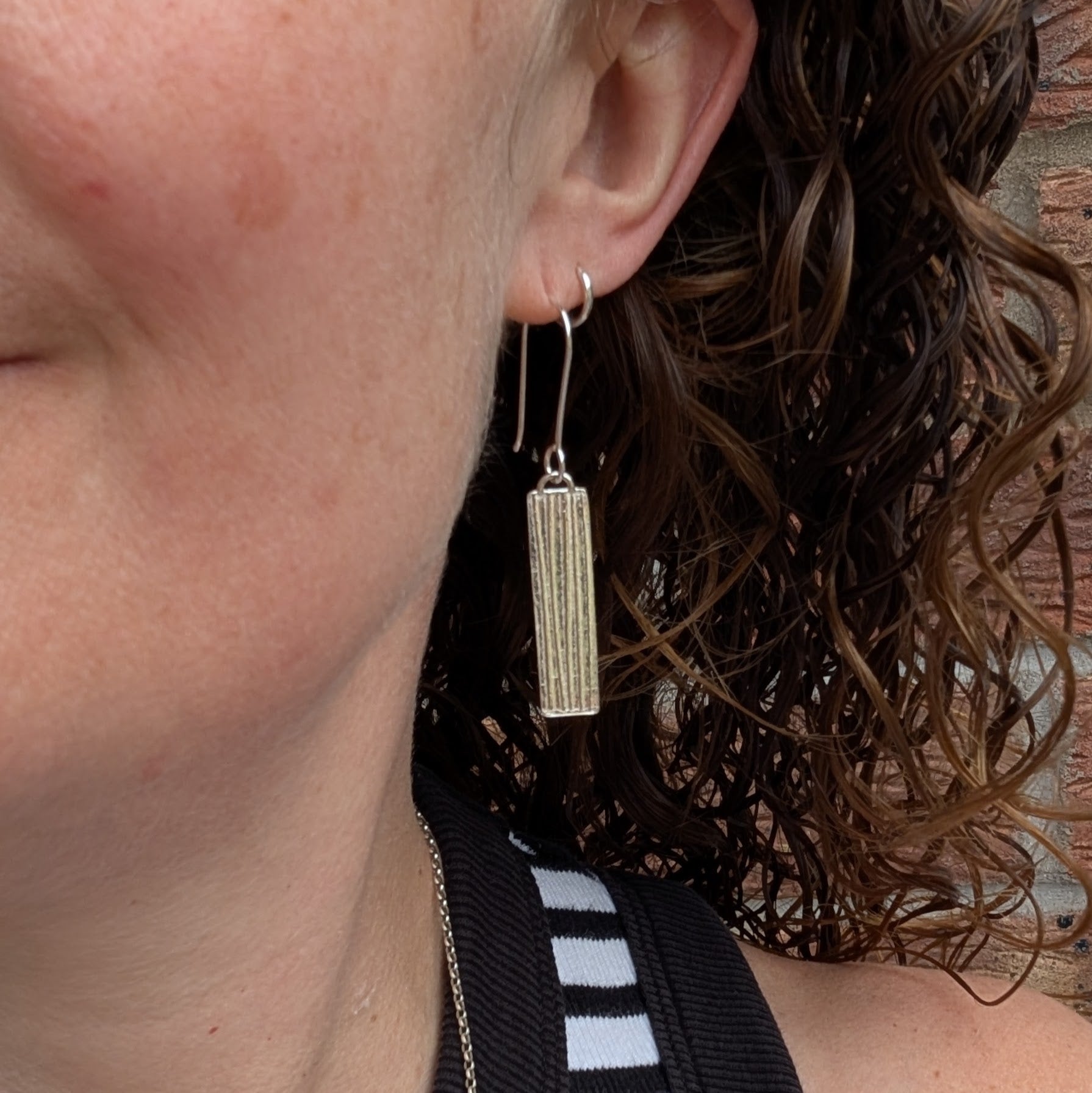 Silver Rectangle Earrings with Ribbon Pattern worn on ear showing length and fit