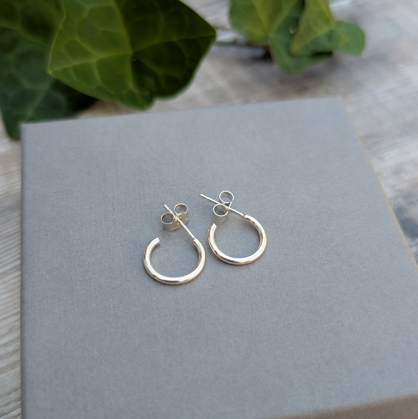 Silver small smooth hoop earrings handmade from recycled Sterling Silver displayed on a grey jewellery box.