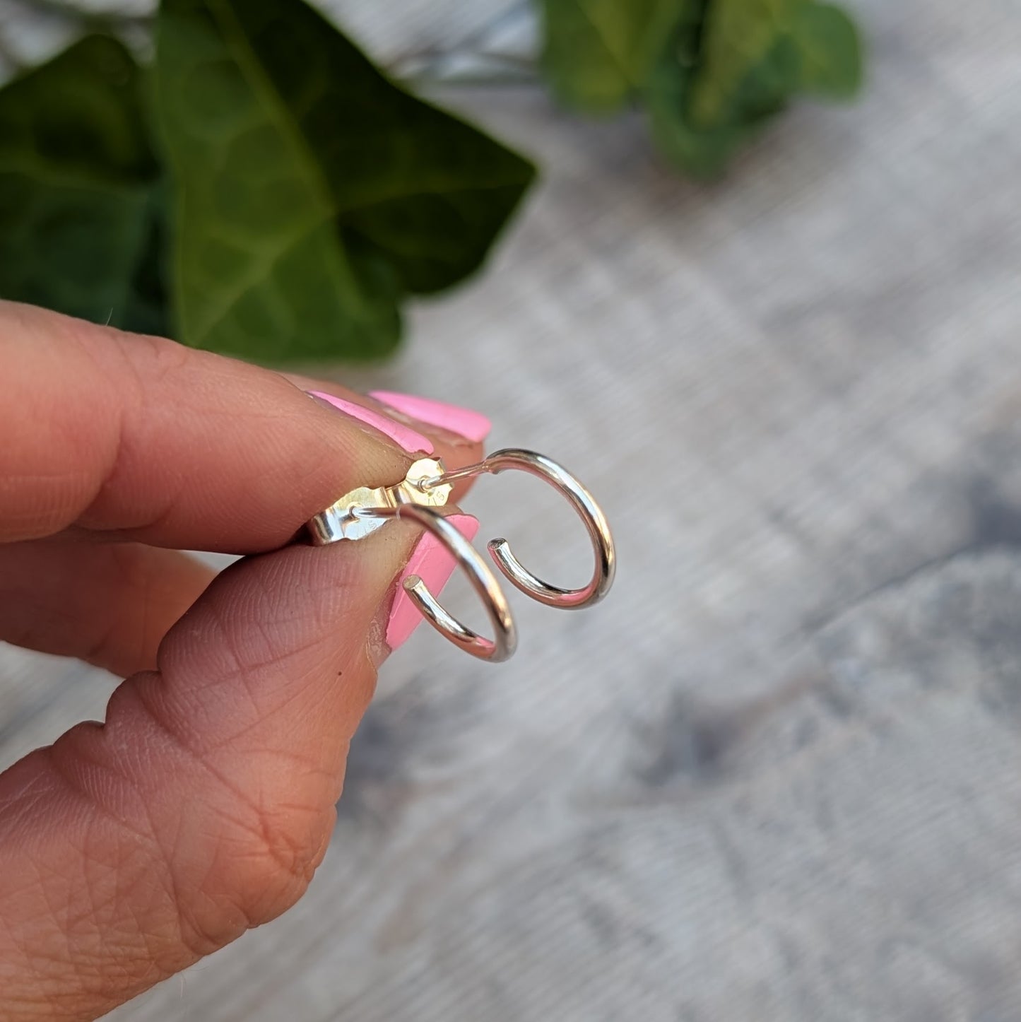 Side view of Silver small smooth hoop earrings handmade from recycled Sterling Silver showing the smooth rounded profile and stud fittings.