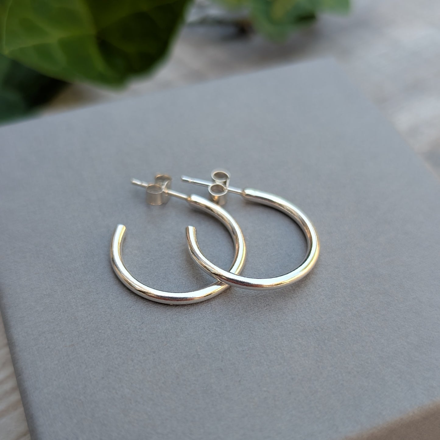 Silver smooth hoop earrings handmade from recycled Sterling Silver displayed on a grey jewellery box.