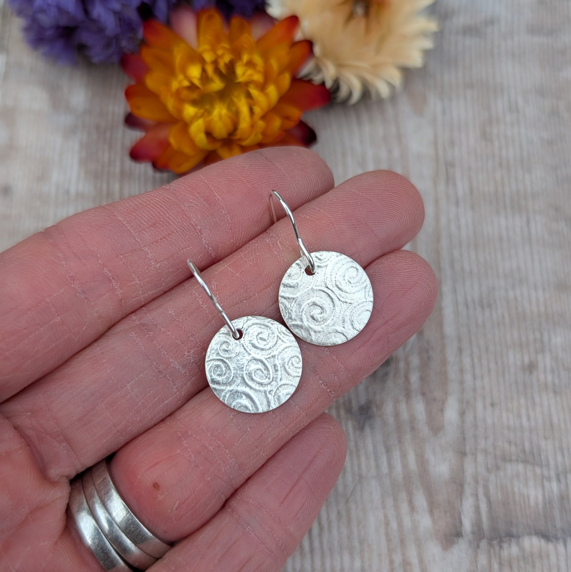 Silver Spiral Pattern Disc Earrings held in a hand, showing spiral texture on round recycled sterling silver discs