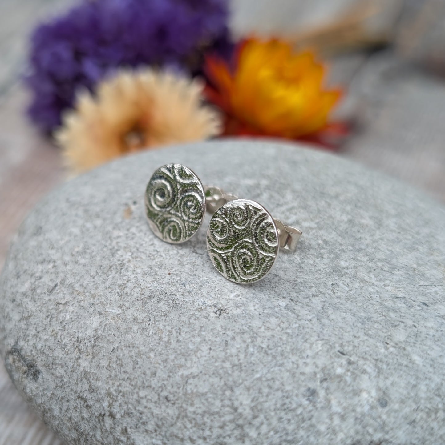 Silver Spiral Pattern Disc Stud Earrings on a stone, showing textured spiral pattern and stud backs