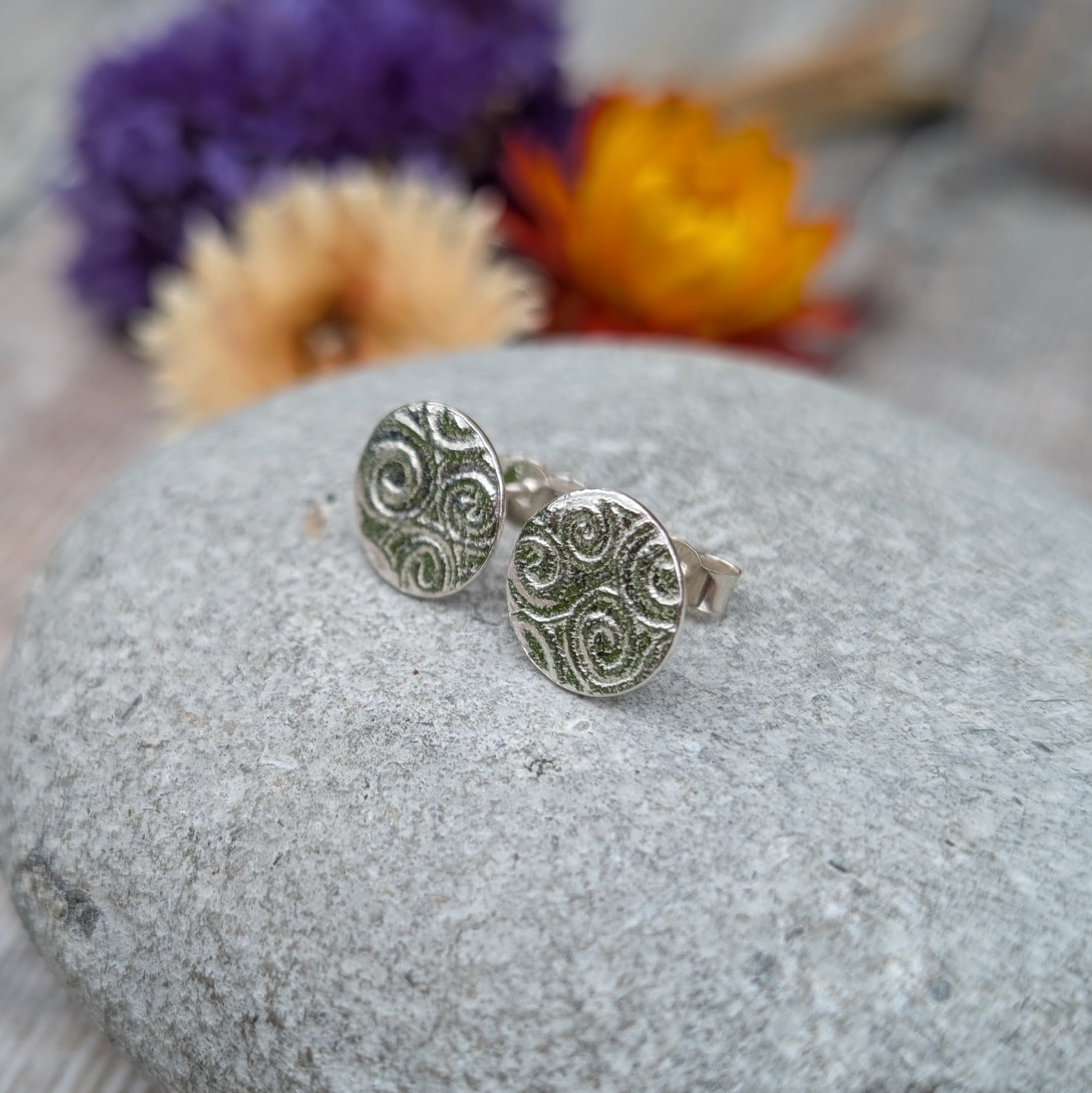 Silver Spiral Pattern Disc Stud Earrings on a stone, showing textured spiral pattern and stud backs