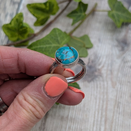 Silver Sunburst Stamped Ring with Turquoise held between fingers showing blue Mohave Turquoise stone and chevron stamped silver band