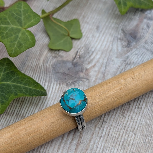 Silver Sunburst Stamped Ring with Turquoise resting on wooden mandrel with ivy leaves background
