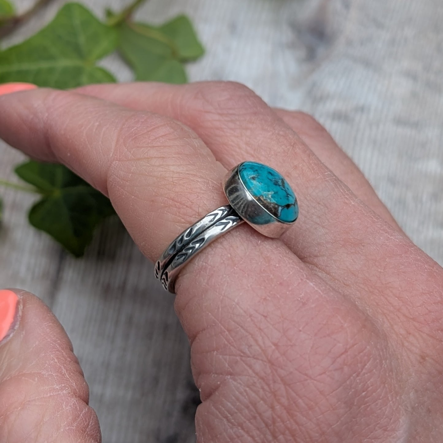 Angled view of Silver Sunburst Stamped Ring with Turquoise on hand showing chevron band pattern and stone setting