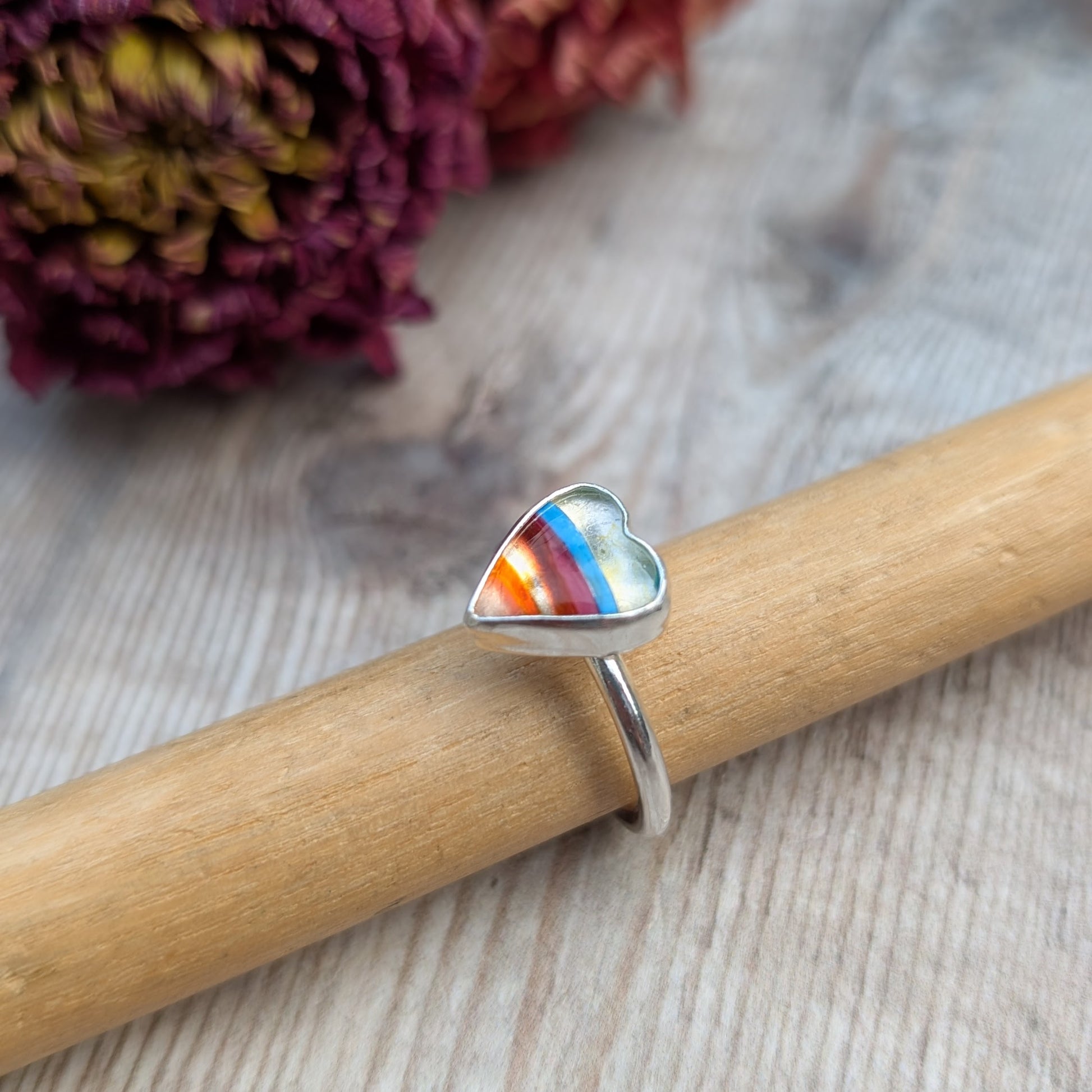 Surfite silver heart ring displayed on a ring mandrel with a wood background.