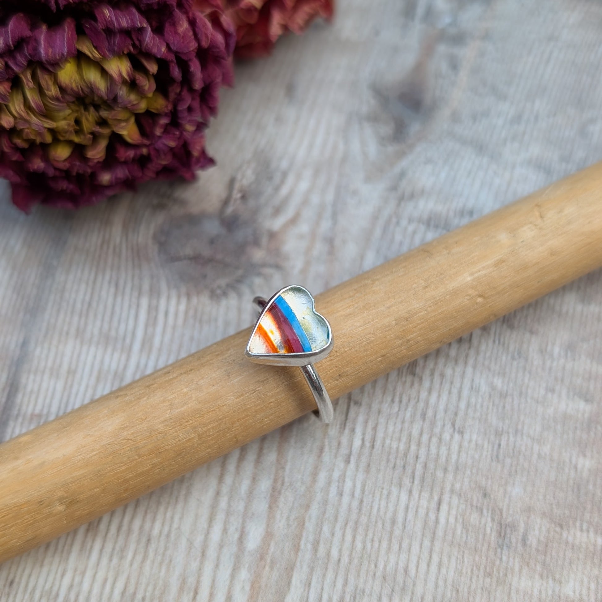 Surfite silver heart ring displayed on a ring mandrel with a wood background.
