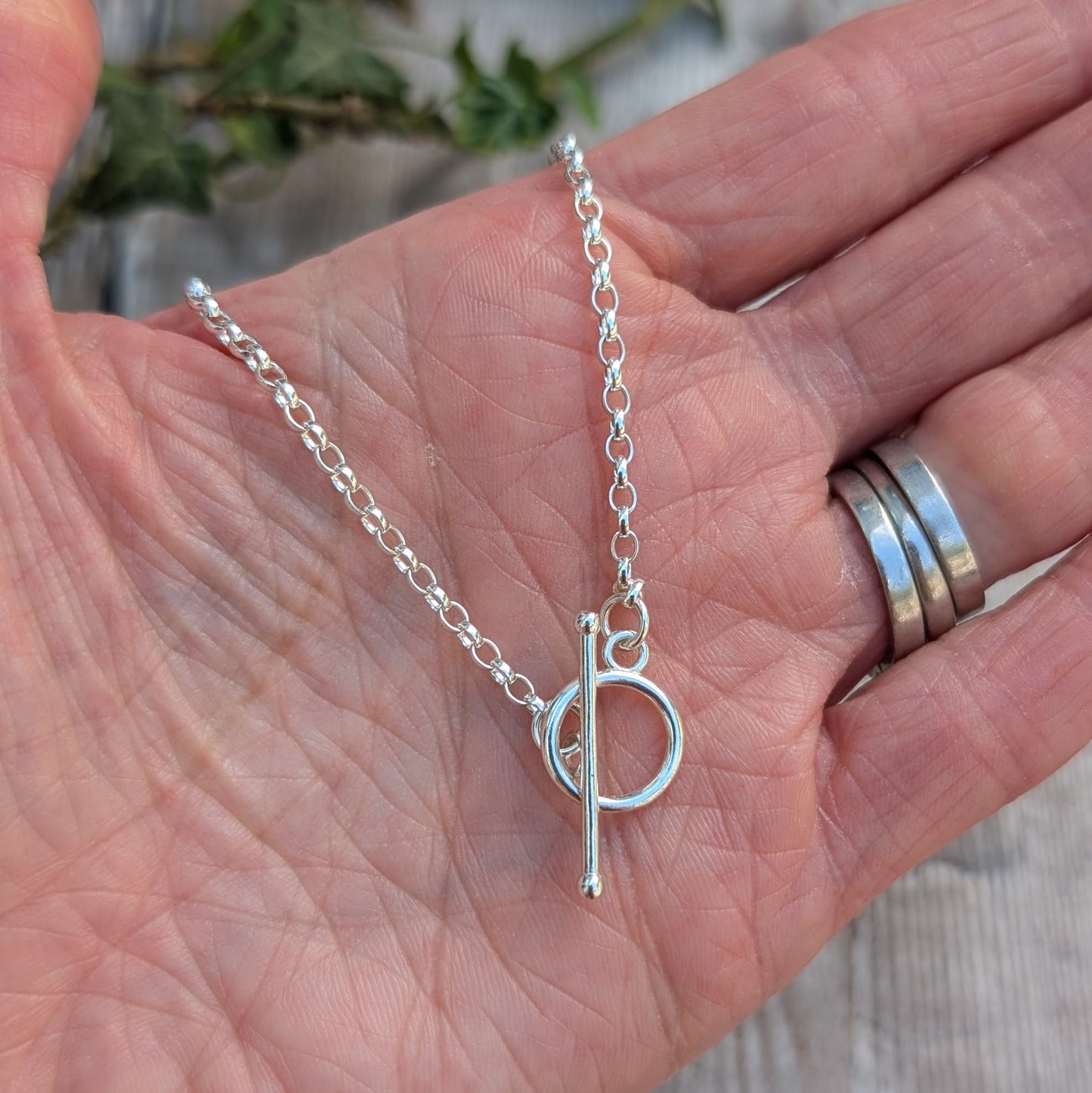 Silver T Bar Necklace handmade from recycled Sterling Silver, displayed in the palm of a hand showing the sterling silver chain and T bar clasp.
