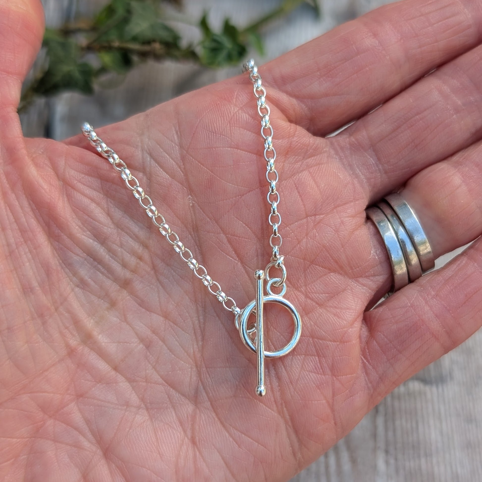 Silver T Bar Necklace handmade from recycled Sterling Silver, displayed in the palm of a hand showing the sterling silver chain and T bar clasp.