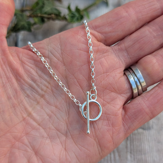Silver T Bar Necklace handmade from recycled Sterling Silver, displayed in the palm of a hand showing the sterling silver chain and T bar clasp.
