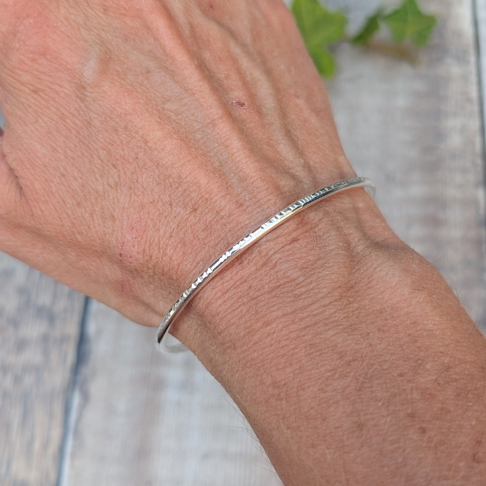 Silver Textured Oval Cuff Bangle worn on the wrist, showing the handmade hammered edge detail and smooth Sterling Silver finish.