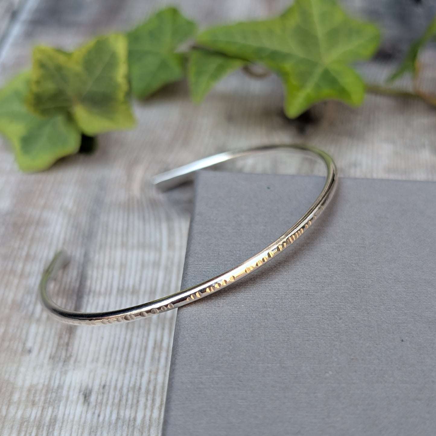 Side view of Silver Textured Oval Cuff Bangle showing the handmade textured edge and smooth silver surface.