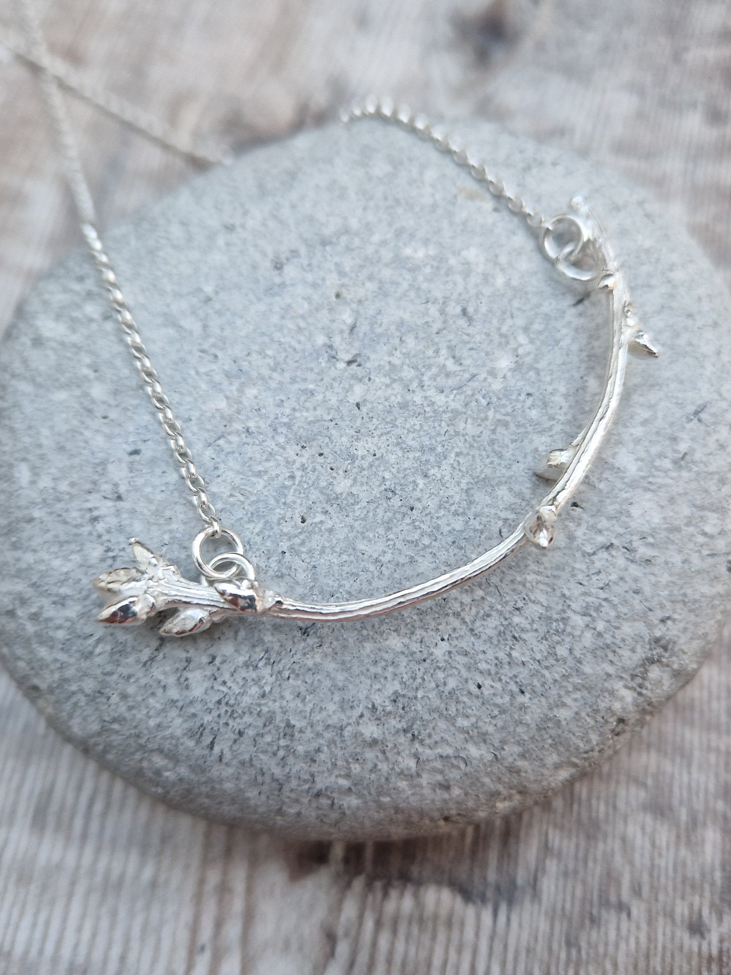 Pendant is a Sterling Silver twig/branch in bud along the stem and a larger bud at the end, curved in shape, attached to silver chain via two small circle links at each end of the branch.