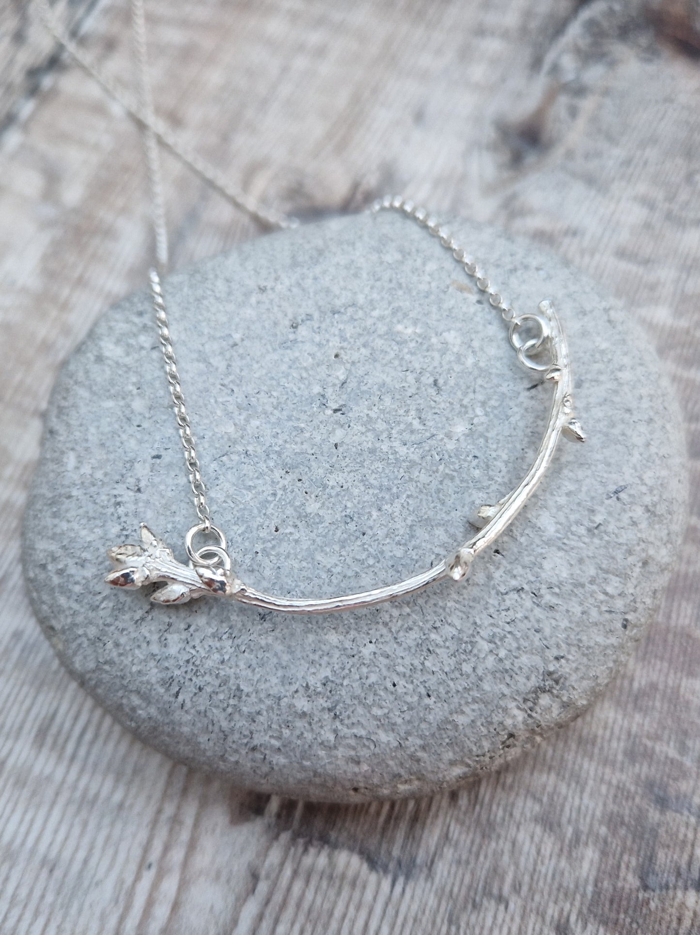 Pendant is a Sterling Silver twig/branch in bud along the stem and a larger bud at the end, curved in shape, attached to silver chain via two small circle links at each end of the branch.