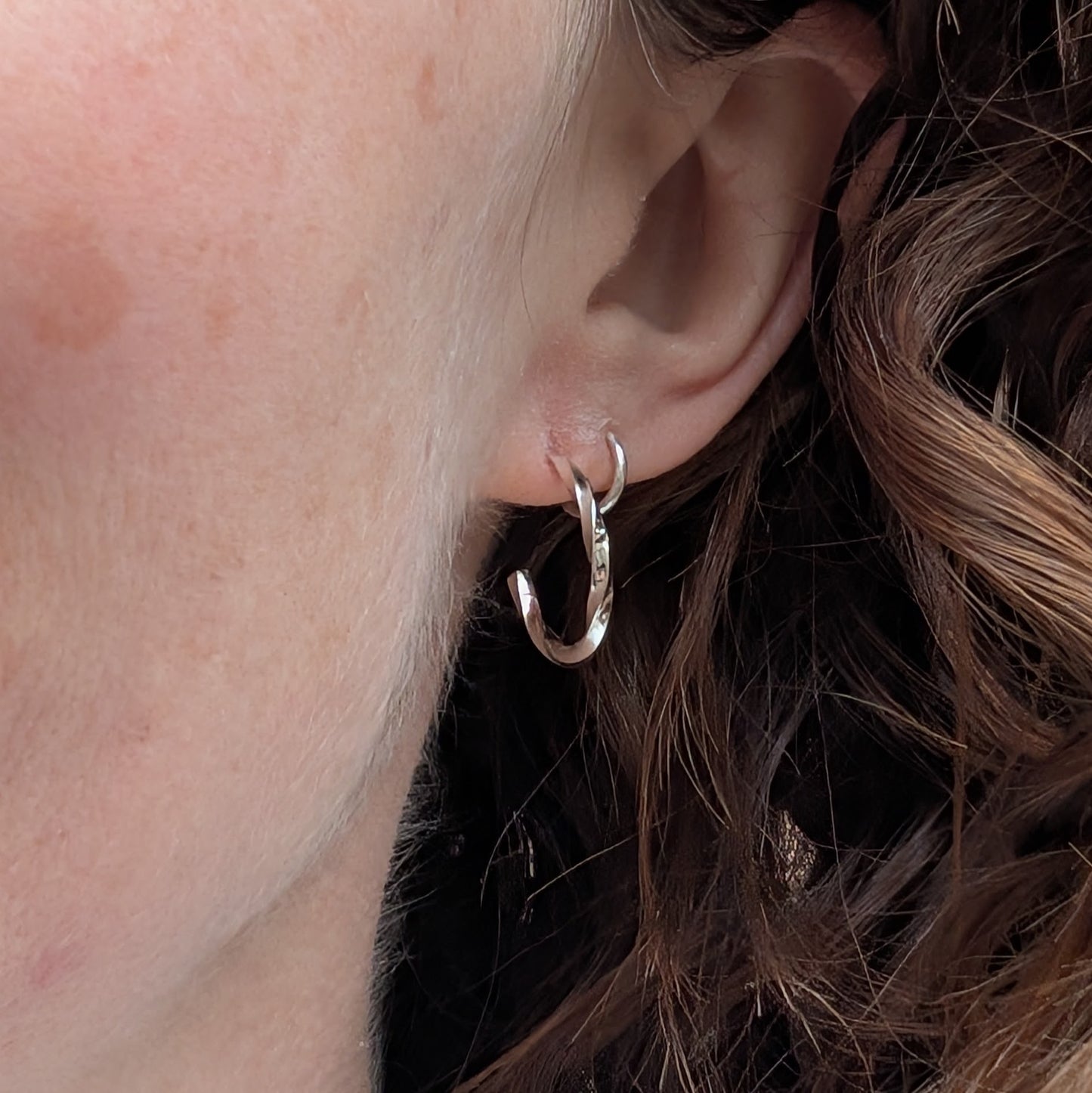 Small twisted sterling silver hoop earring worn in the ear, showing how the hoop sits when worn.