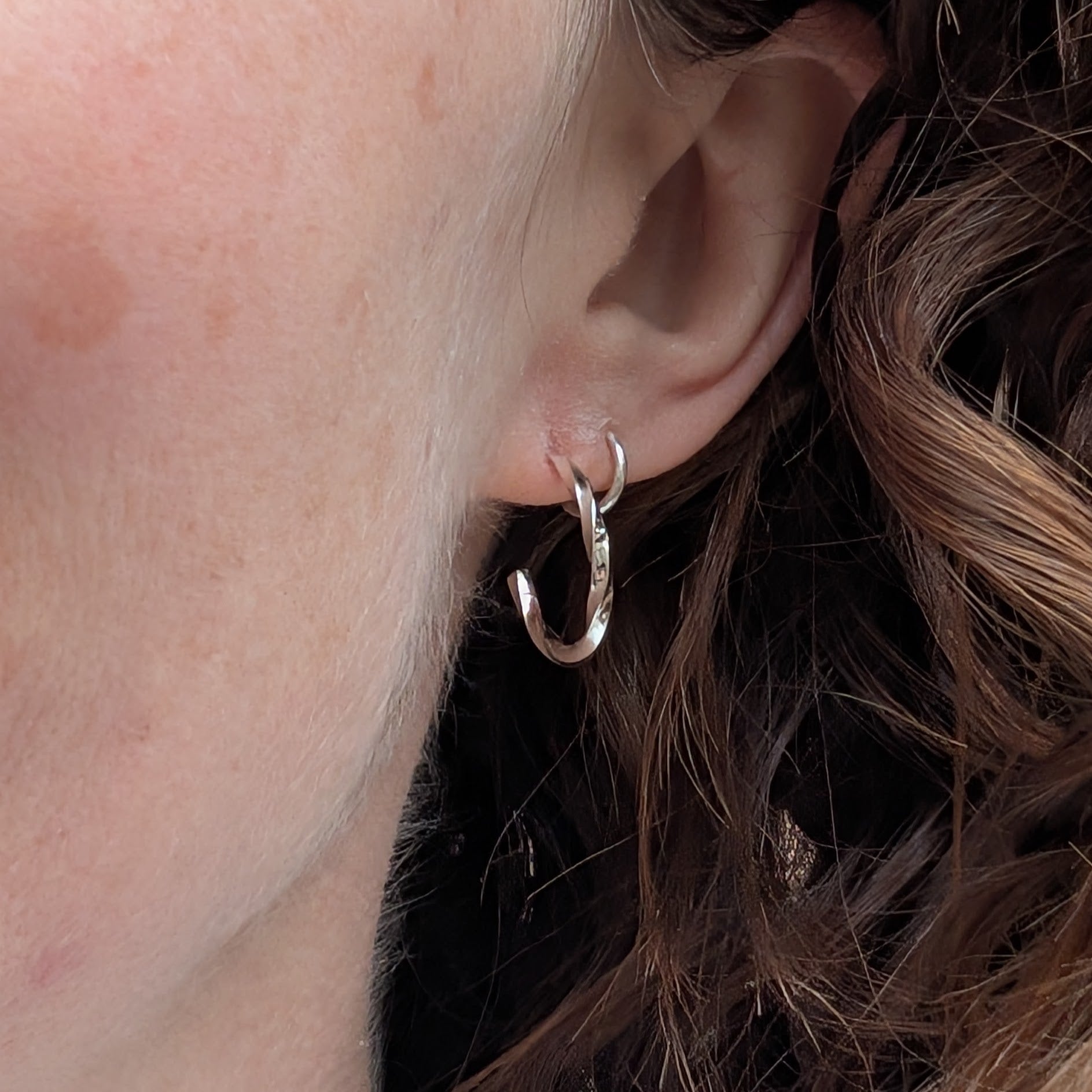 Small twisted sterling silver hoop earring worn in the ear, showing how the hoop sits when worn.