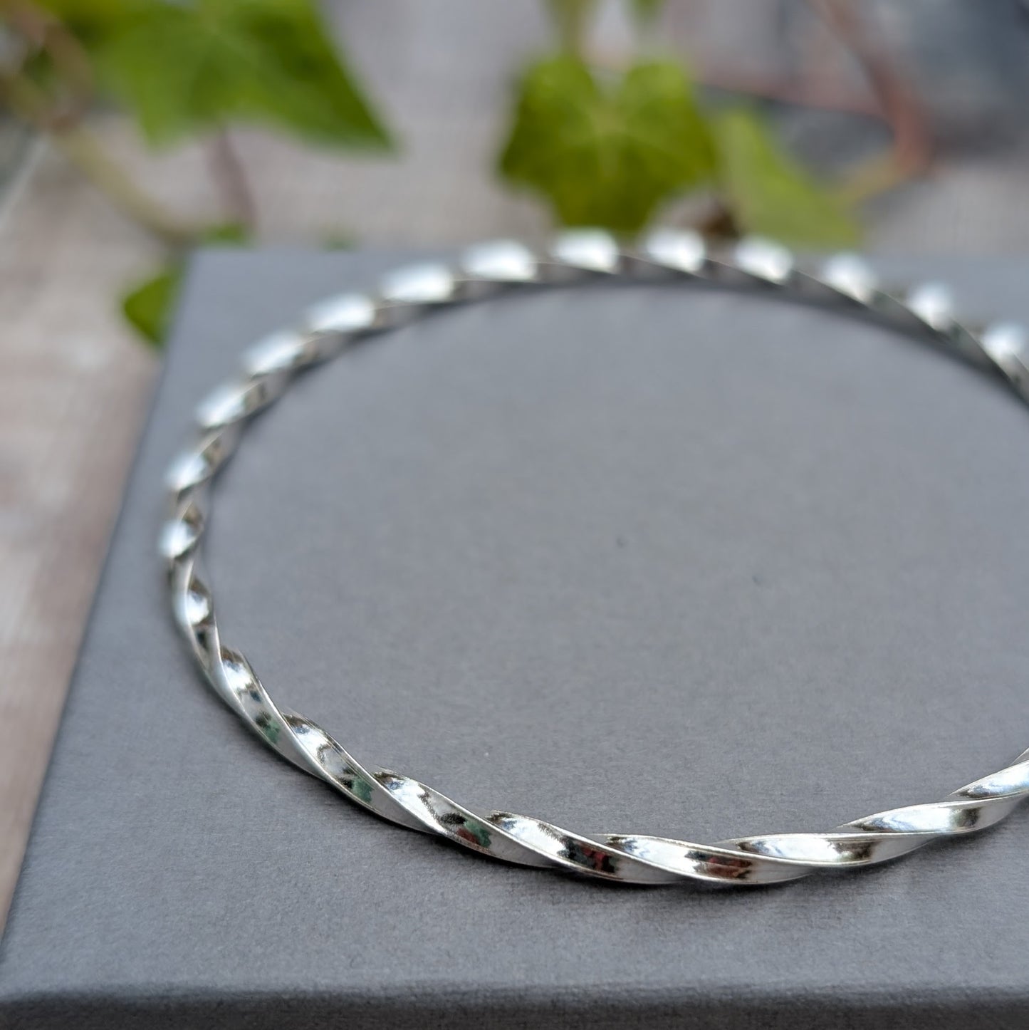 Close up of the Silver Twisted Round Bangle handmade from recycled Sterling Silver 2mm square wire, highlighting the polished twisted finish.