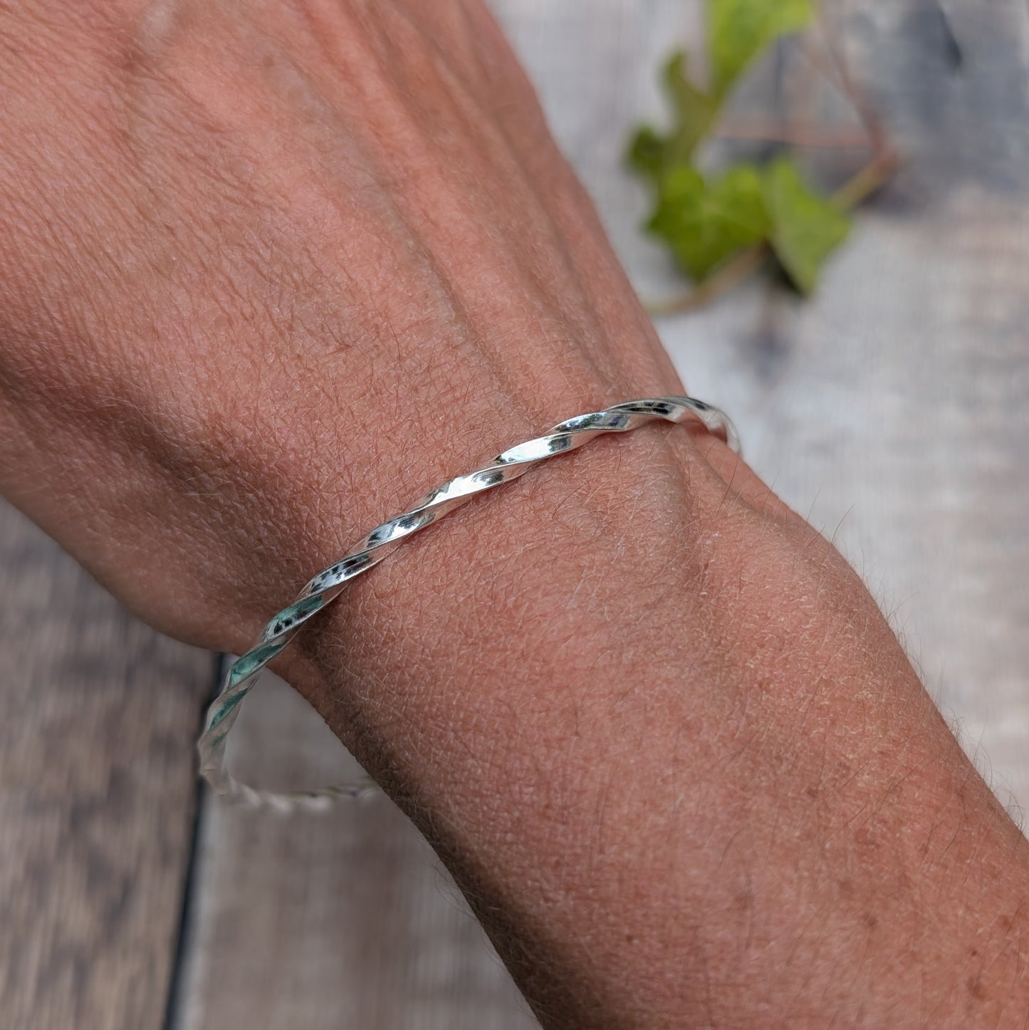Silver Twisted Round Bangle handmade from recycled Sterling Silver 2mm square wire, worn on the wrist to show the fit.