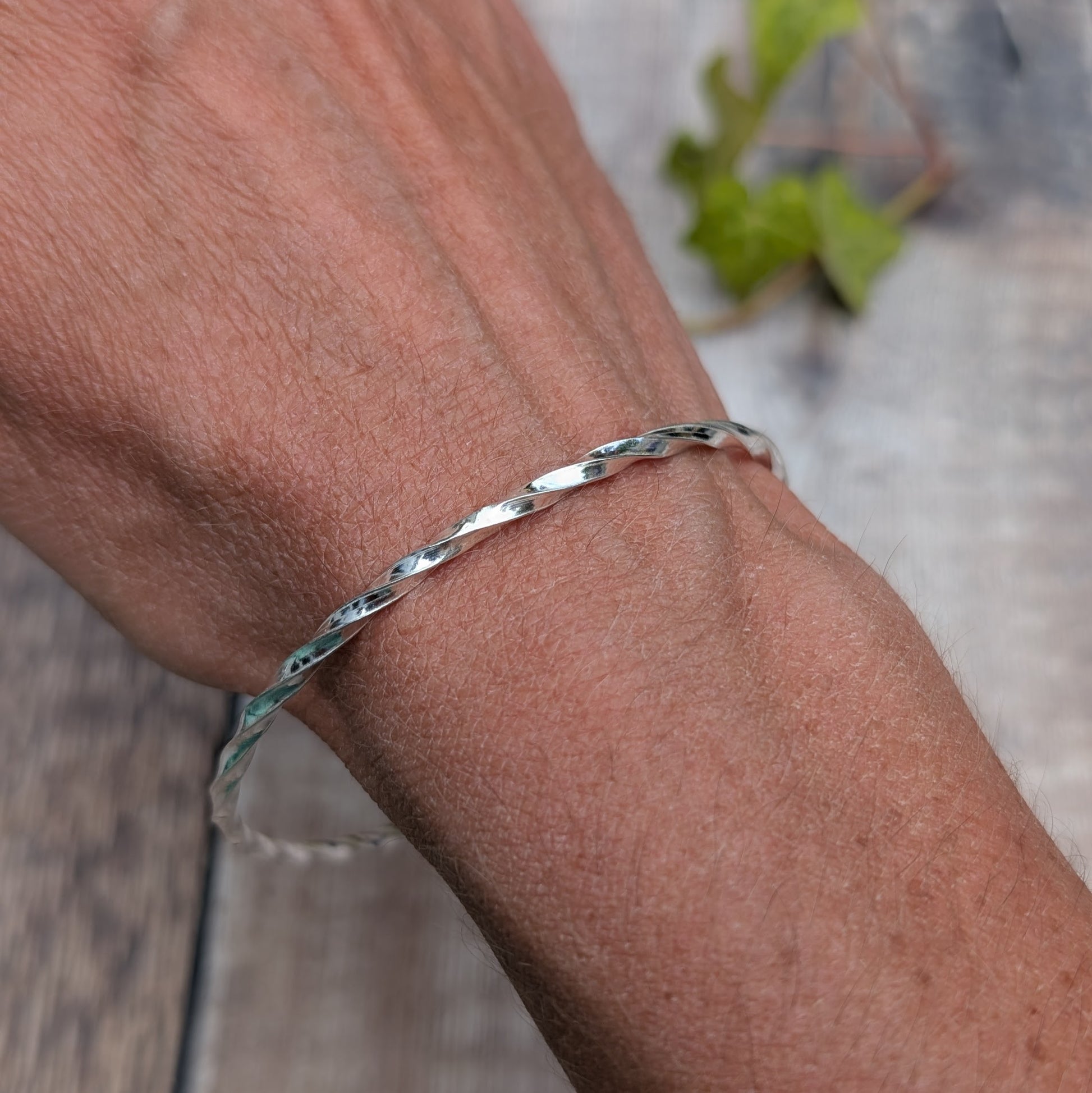 Silver Twisted Round Bangle handmade from recycled Sterling Silver 2mm square wire, worn on the wrist to show the fit.