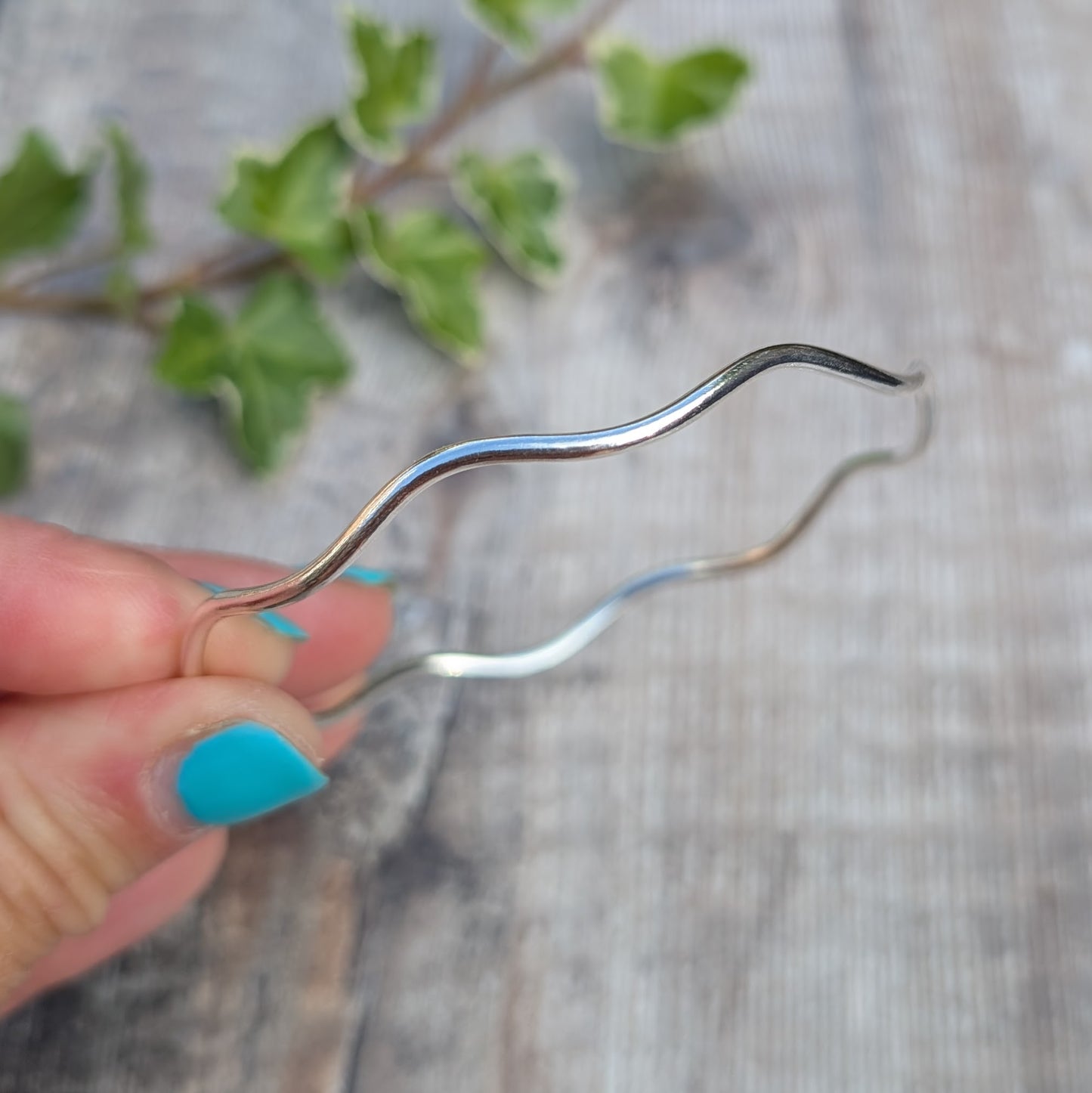 Silver Wavy Round Bangle handmade from recycled Sterling Silver 2mm wire, shown held in a hand to highlight the flowing wavy design.