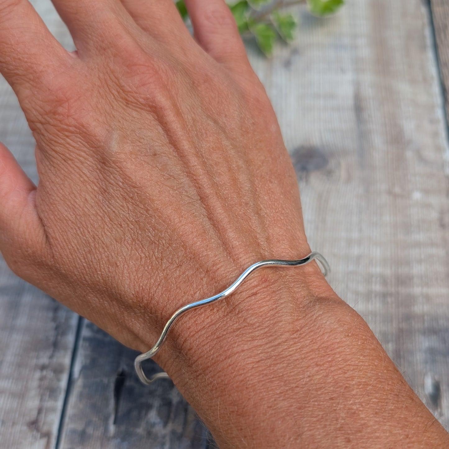 Silver Wavy Round Bangle handmade from recycled Sterling Silver worn on a wrist, showing the elegant wavy design and fit.