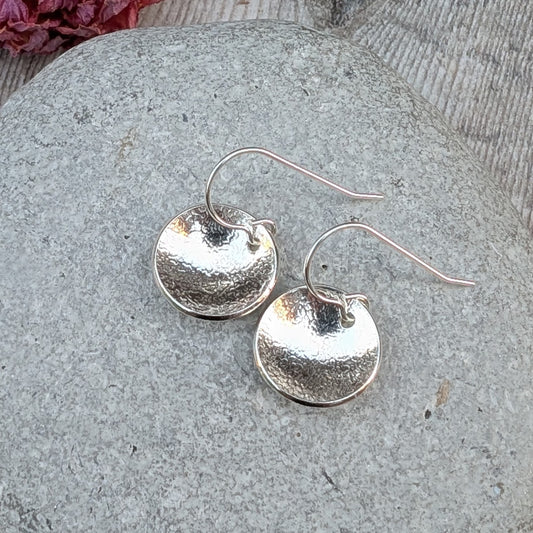 Silver Textured Dome Disc Earrings showing the domed shape and lightly textured surface on a stone