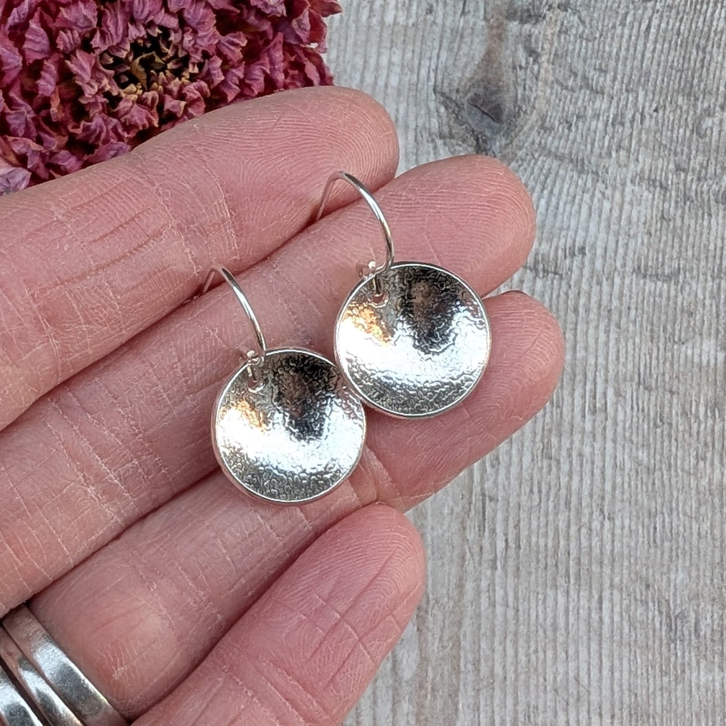Silver Textured Dome Disc Earrings held in the hand, showing size, curve and texture