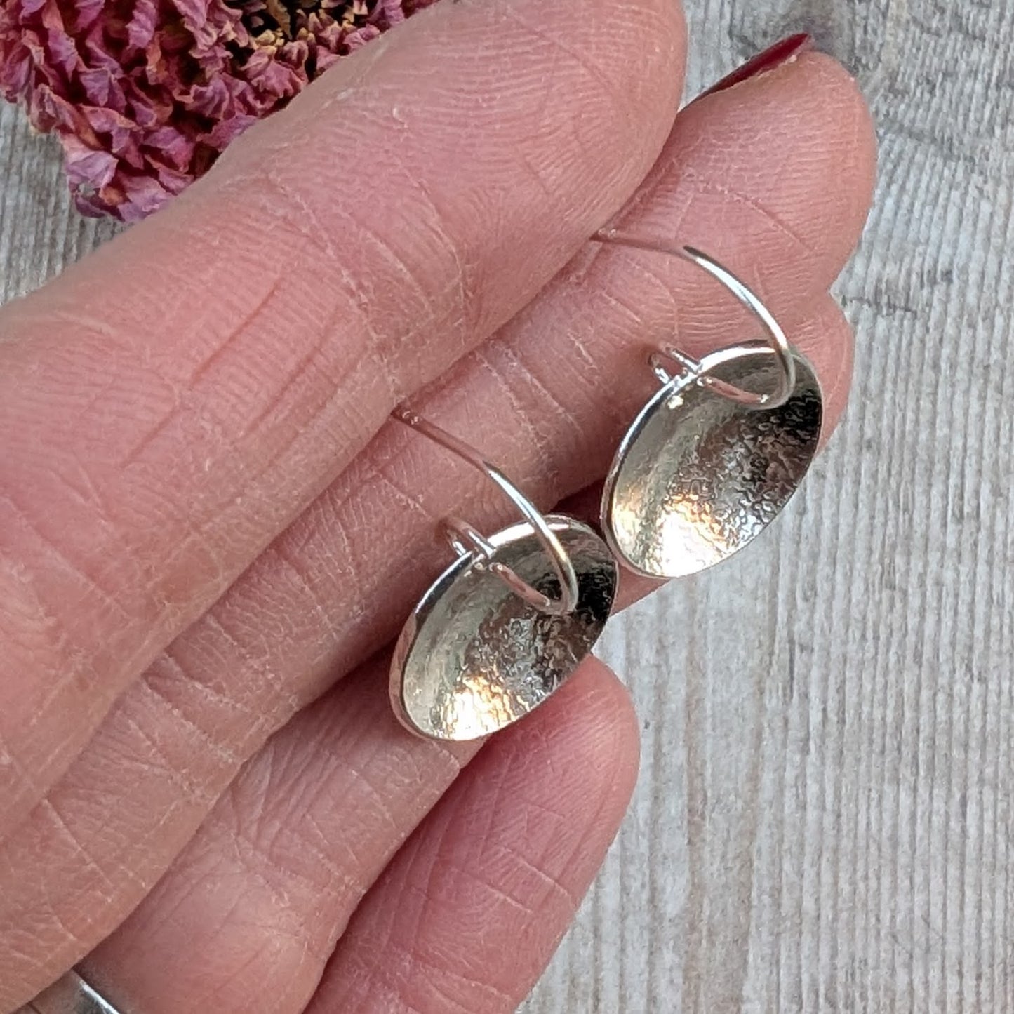Silver Textured Dome Disc Earrings held in the hand, showing size, curve and texture