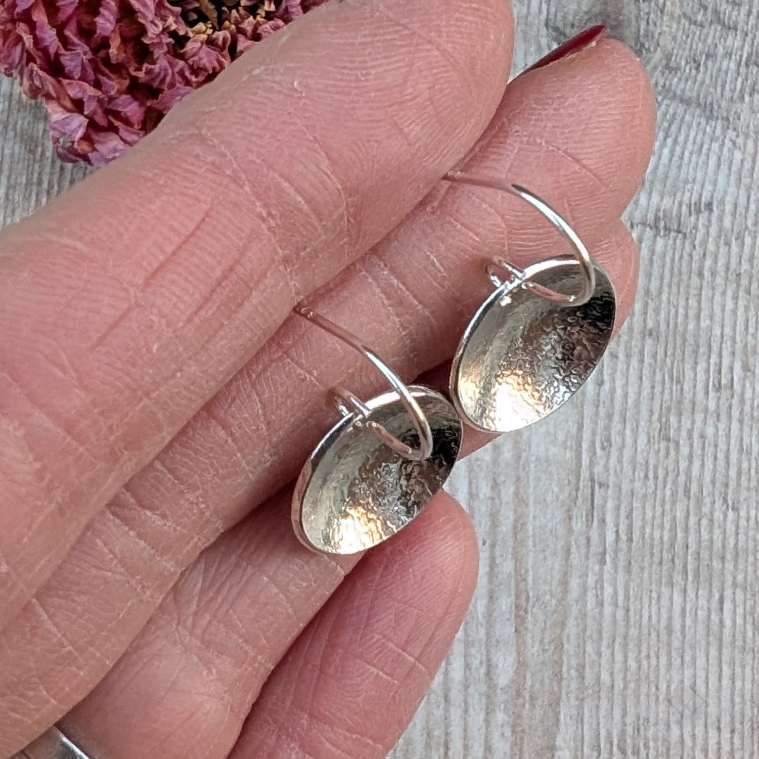Silver Textured Dome Disc Earrings held in the hand, showing size, curve and texture