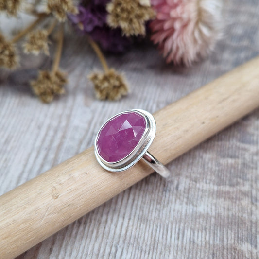 Red Sapphire oval gemstone UK Size R, with diamond cut texture, set in simple silver bezel mounted on top of Sterling Silver band approx. 2mm wide. Sapphire stone is a cloudy mauve colour.