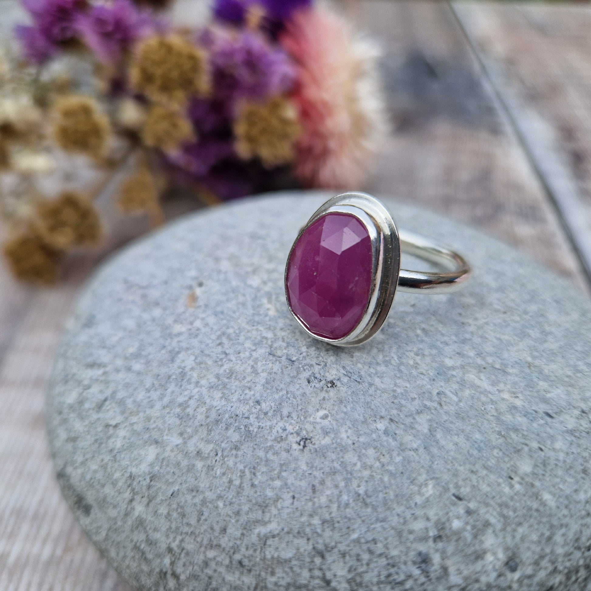 Red Sapphire oval gemstone UK Size R, with diamond cut texture, set in simple silver bezel mounted on top of Sterling Silver band approx. 2mm wide. Sapphire stone is a cloudy mauve colour.