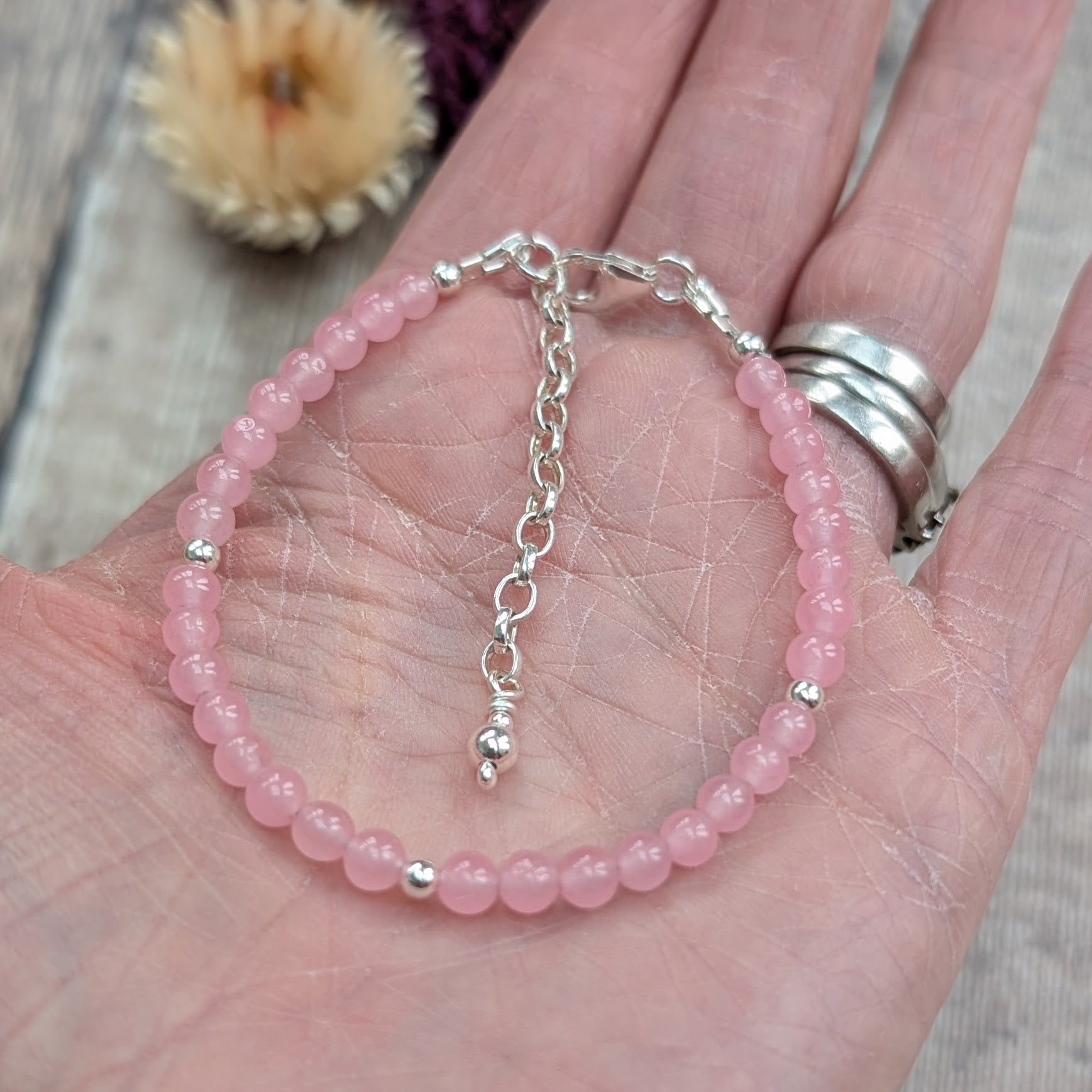 Rose quartz bead bracelet with sterling silver spacer beads and extender chain, shown resting in the palm of a hand.