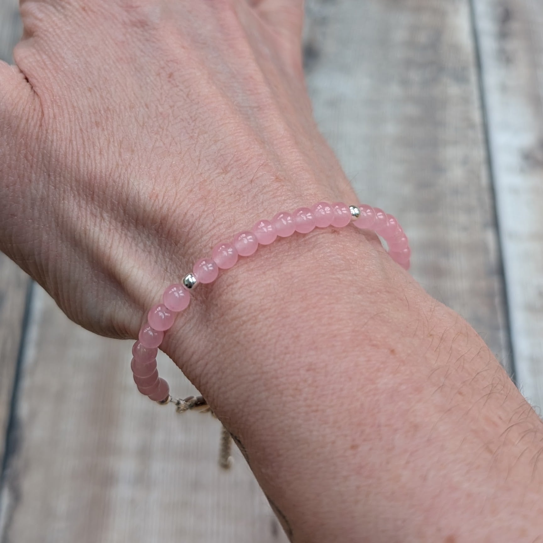 Rose quartz bead bracelet worn on the wrist, showing soft pink stones and subtle sterling silver detailing.