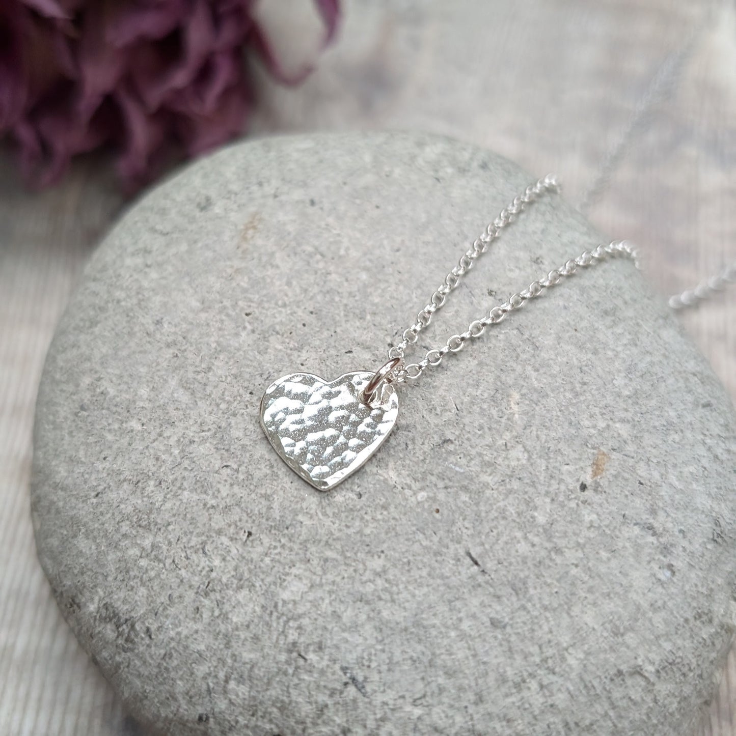 Pendant is sterling silver flat heart shape with hammered texture finish, suspended from a silver chain via small open circle link.