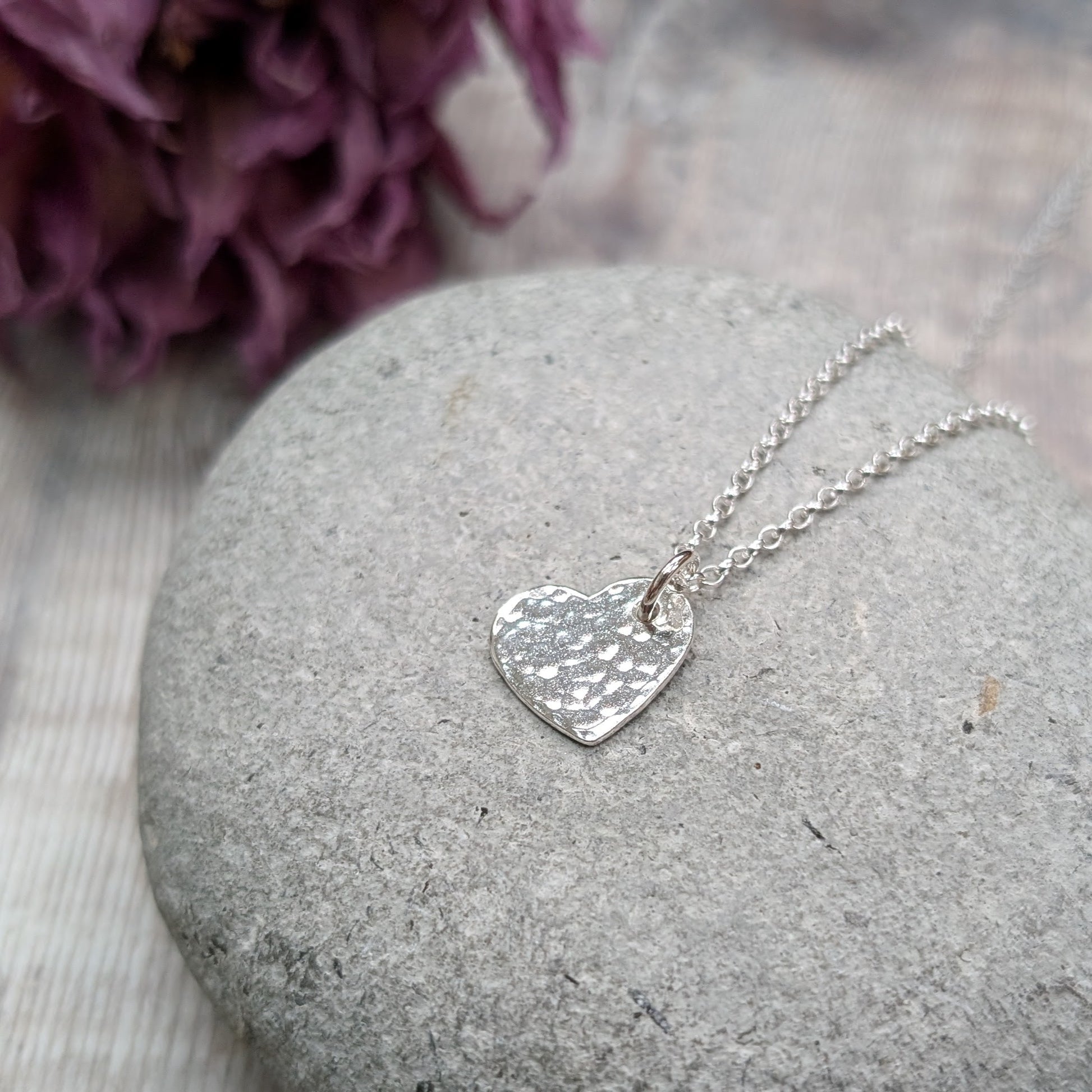 Pendant is sterling silver flat heart shape with hammered texture finish, suspended from a silver chain via small open circle link.