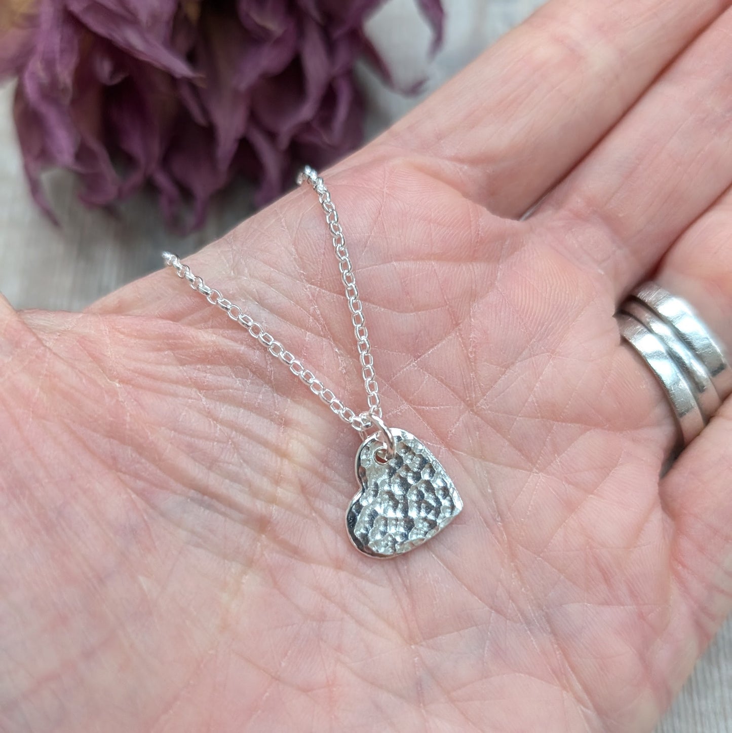 Pendant is sterling silver flat heart shape with hammered texture finish, suspended from a silver chain via small open circle link.