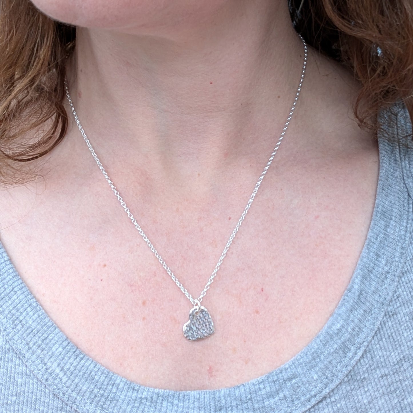 Pendant is sterling silver flat heart shape with hammered texture finish, suspended from a silver chain via small open circle link.