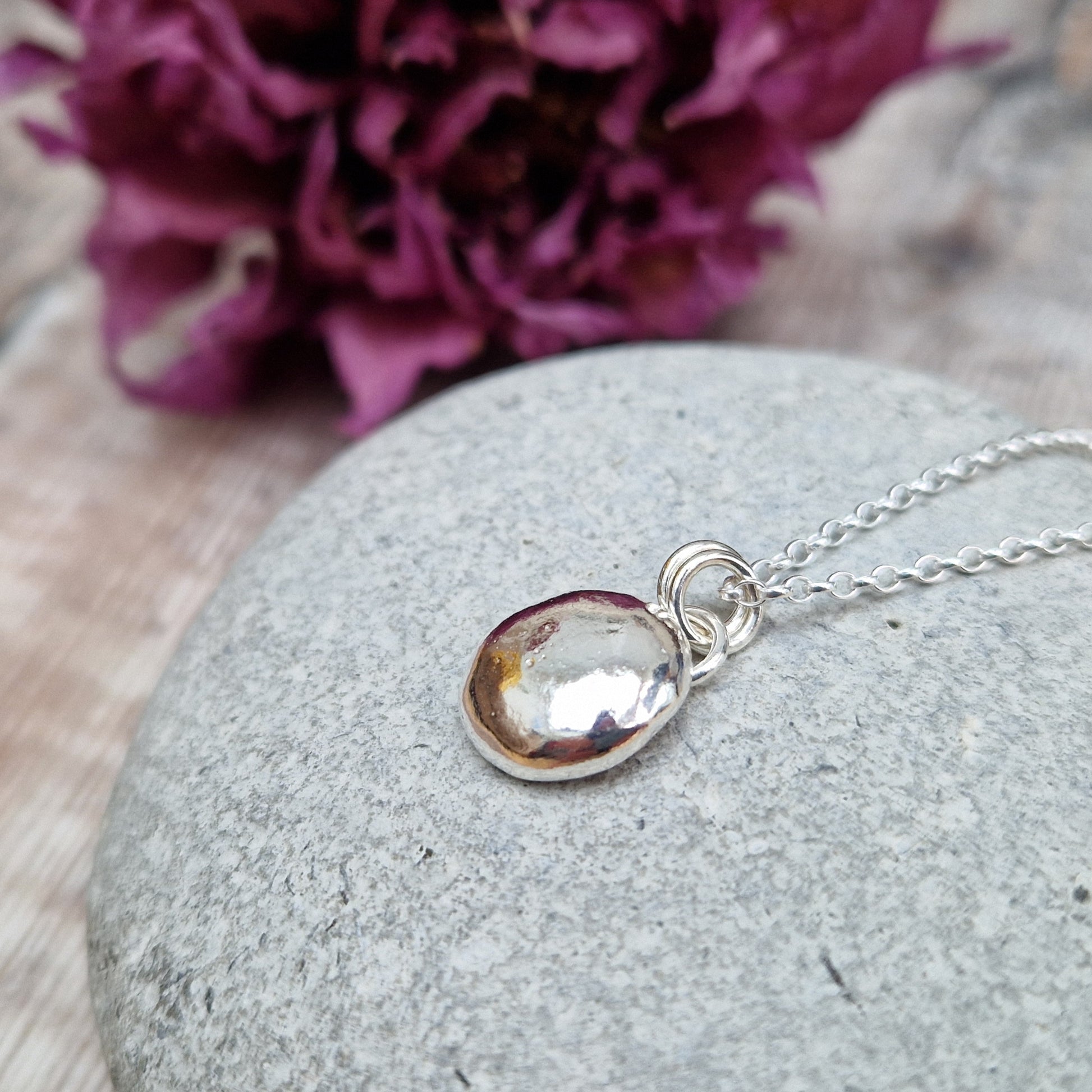 Sterling Silver round pebble shaped pendant with hammered texture, suspended from silver chain via two small circle links.