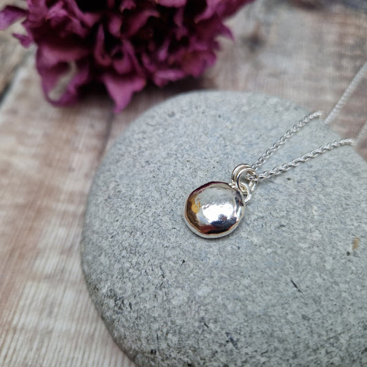 Sterling Silver round pebble shaped pendant with hammered texture, suspended from silver chain via two small circle links.