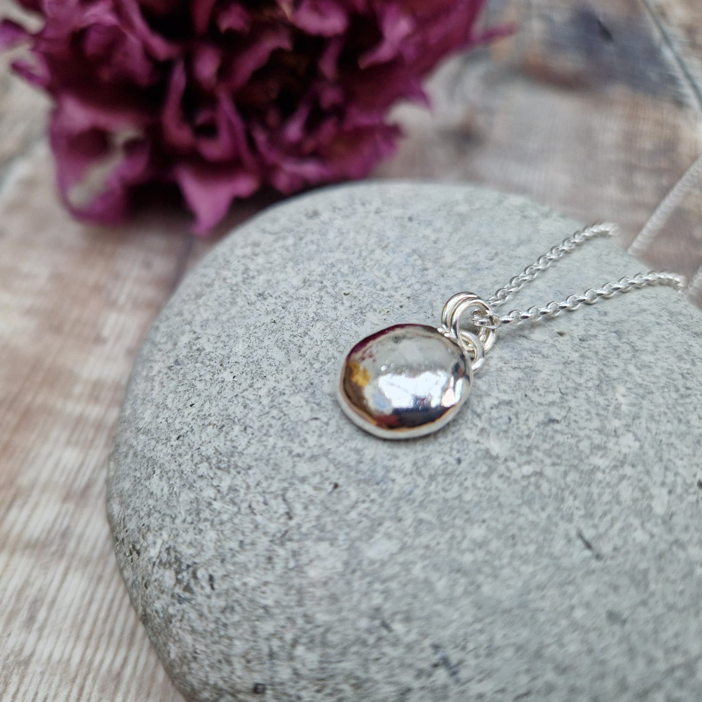 Sterling Silver round pebble shaped pendant with hammered texture, suspended from silver chain via two small circle links.