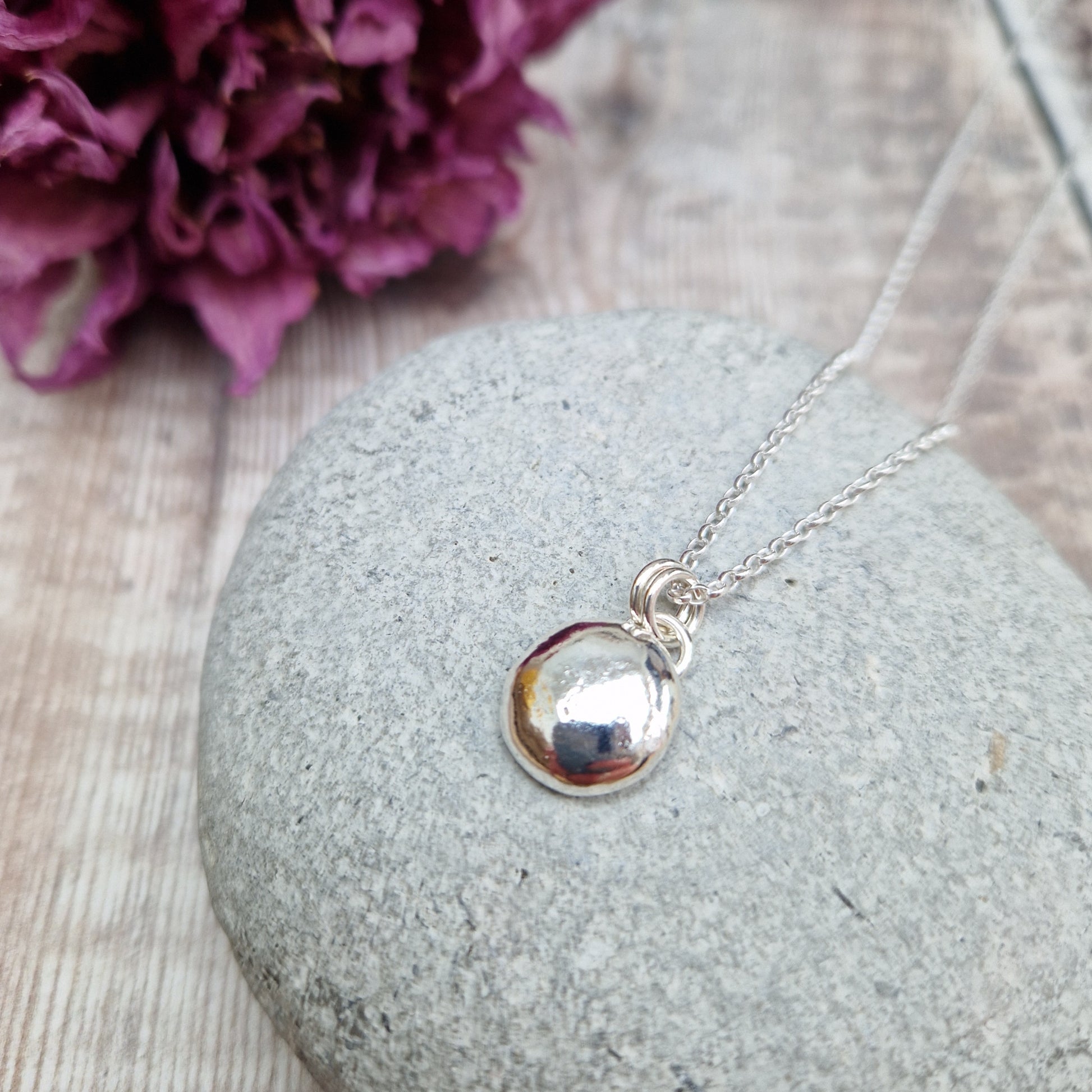 Sterling Silver round pebble shaped pendant with hammered texture, suspended from silver chain via two small circle links.