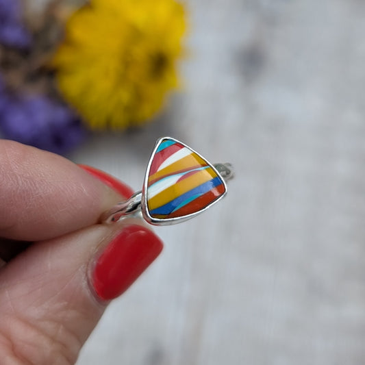 A hand holding the Surfite ring to show its colourful stripes and wave-textured silver band.
