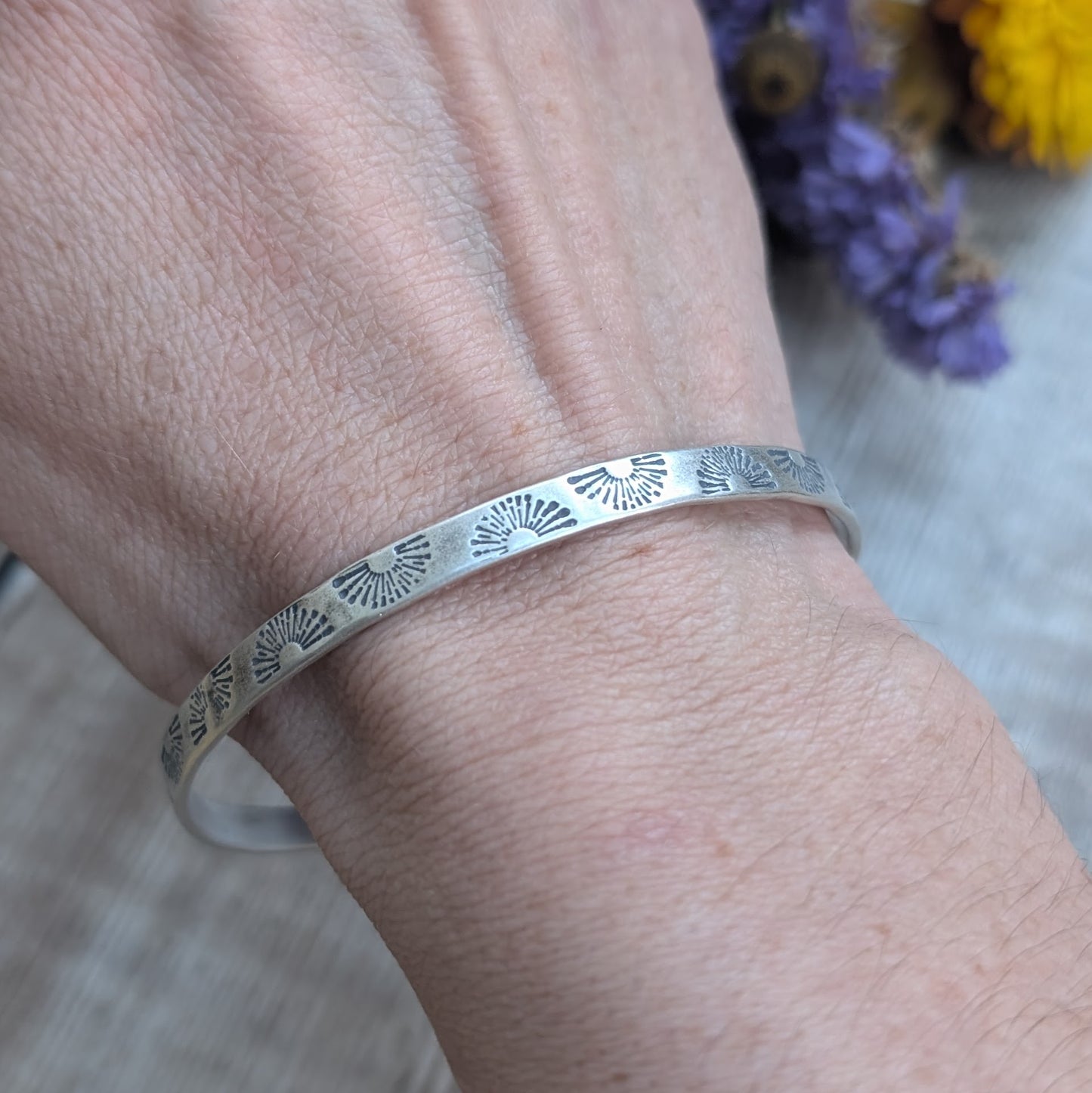 Sterling Silver bangle stamped with repeating sunburst pattern.