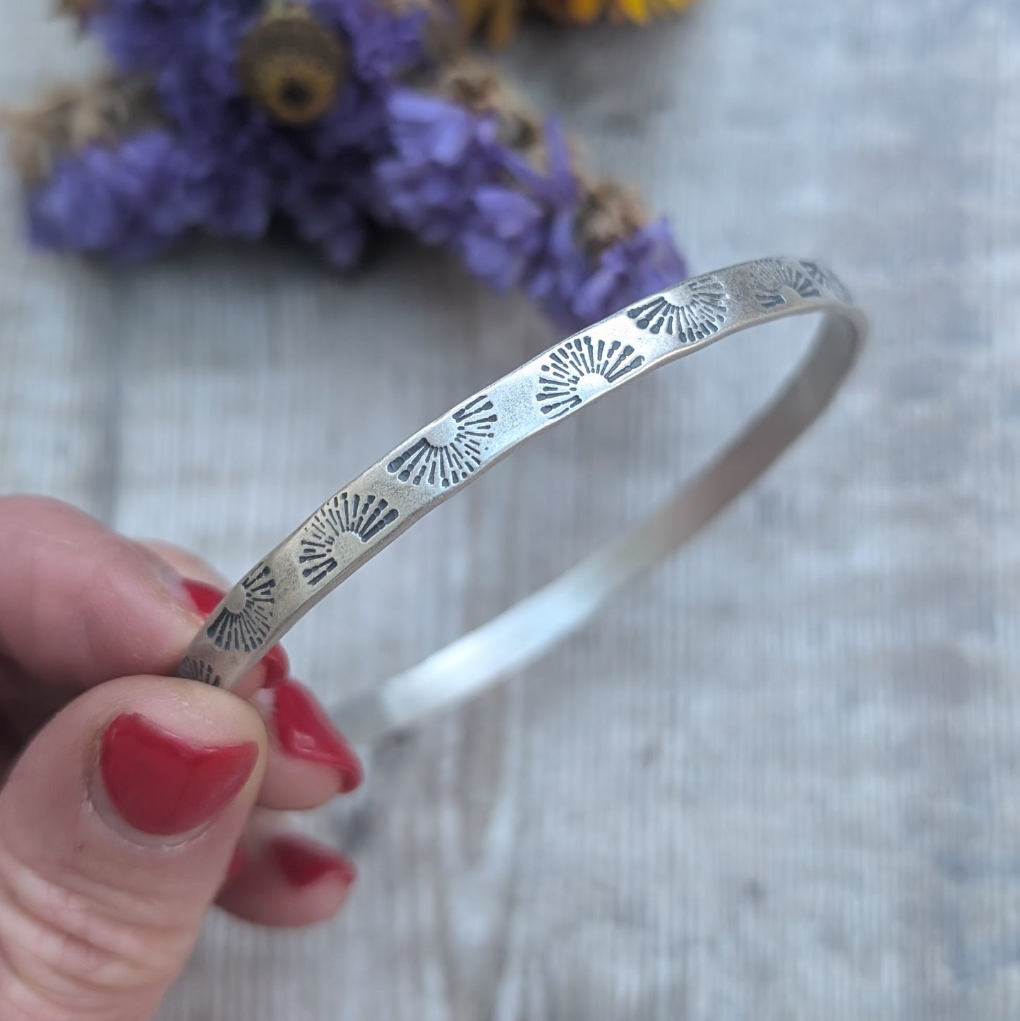 Sterling Silver bangle stamped with repeating sunburst pattern.