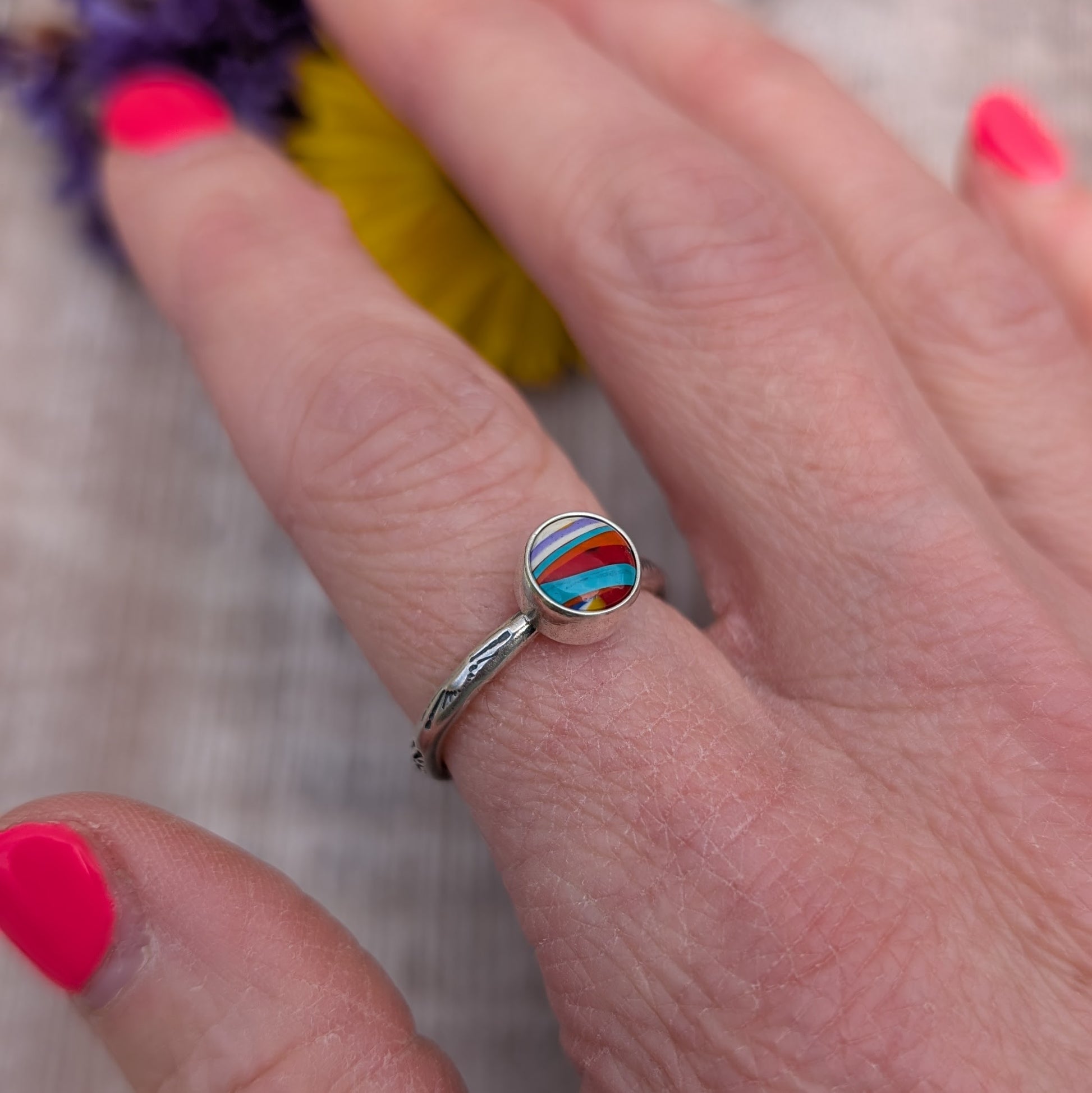 Surfite Ring with Sunburst Stamp on hand, side angle showing the handmade silver band and bright striped Surfite stone.
