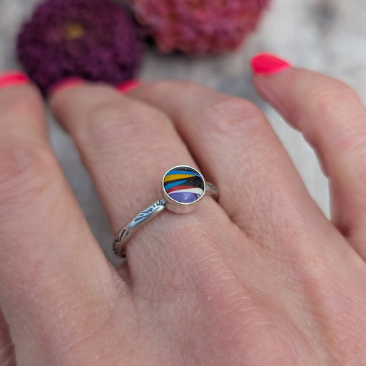 Surfite Ring with Sunburst Stamp worn on finger showing handmade silver band and unique striped Surfite stone