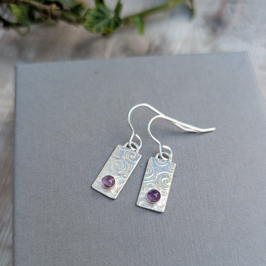 Swirly Rectangle Patterned Earrings with Amethyst handmade from recycled Sterling Silver, shown on a grey display card with a hand-stamped swirly pattern and round purple Amethyst stones.
