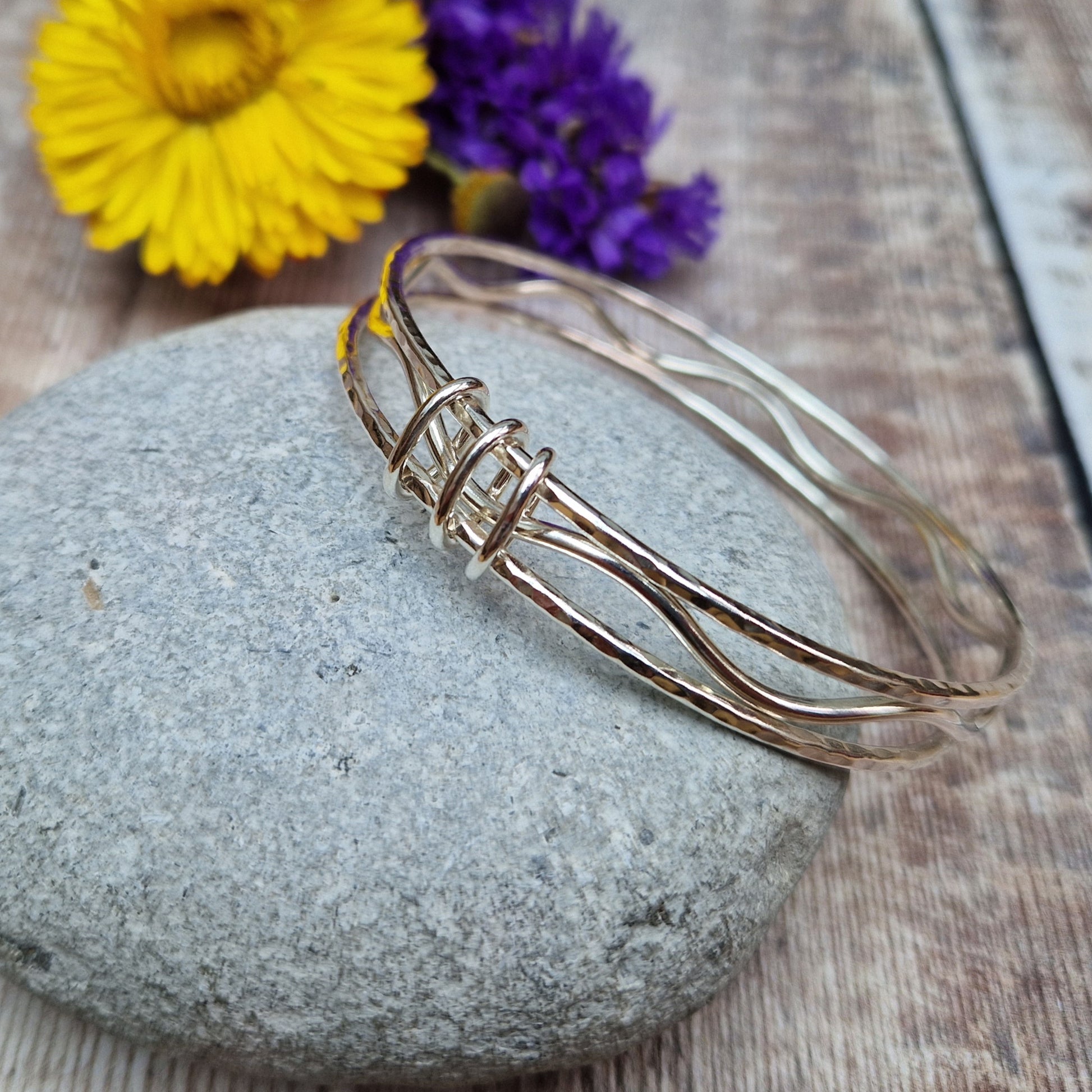 Three sterling silver bangles with hammered texture, centre bangle is wavy. Bangles are joined by three oval shaped links.